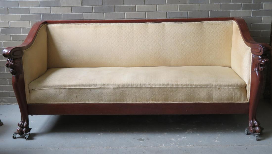 Classical Empire sofa having a mahogany crest rail that: Classical Empire sofa having a mahogany crest rail that leads to carved arms over a lion's head leading to heavily carved claw feet. - Circa 1860. Some surface scratches and small wear area to side of