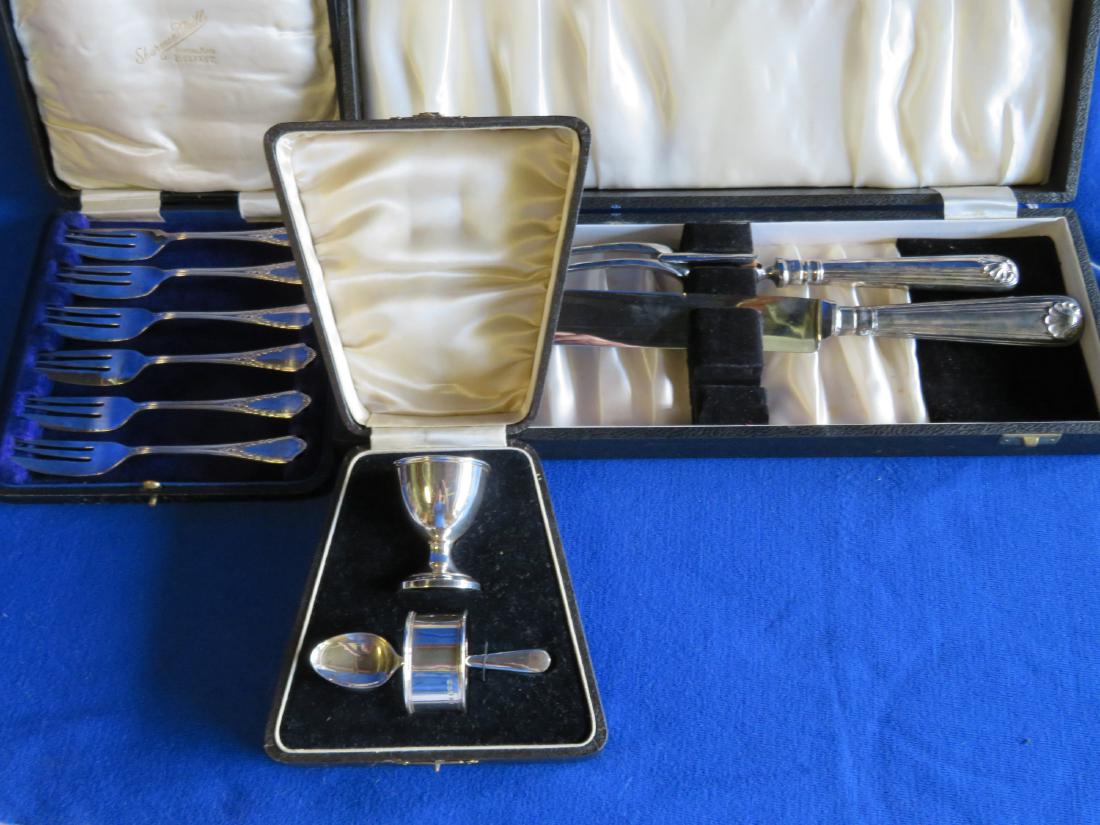 Three boxed sets of silver including: 1) Set of six: Three boxed sets of silver including: 1) Set of six plated fish forks signed S.D. Neils, Belfast (Sharmon D. Neills); 2) Three piece Sterling child's set including spoon, egg cup, and napkin ring with