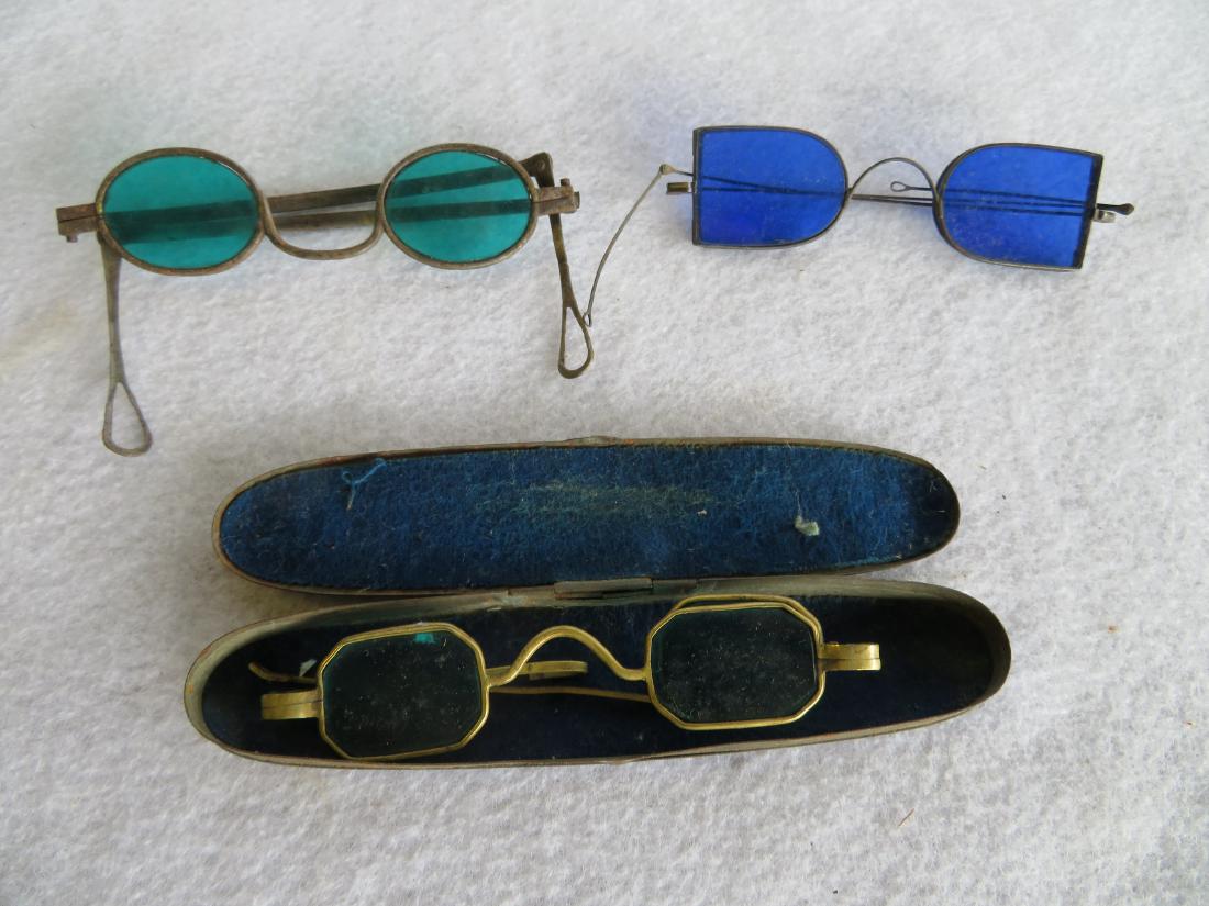 Three pair of eye glasses with colored lenses including: Three pair of eye glasses with colored lenses including pair with green lenses - some surface rust on frame, else very good condition, pair with blue lenses - some surface rust on frame else very good