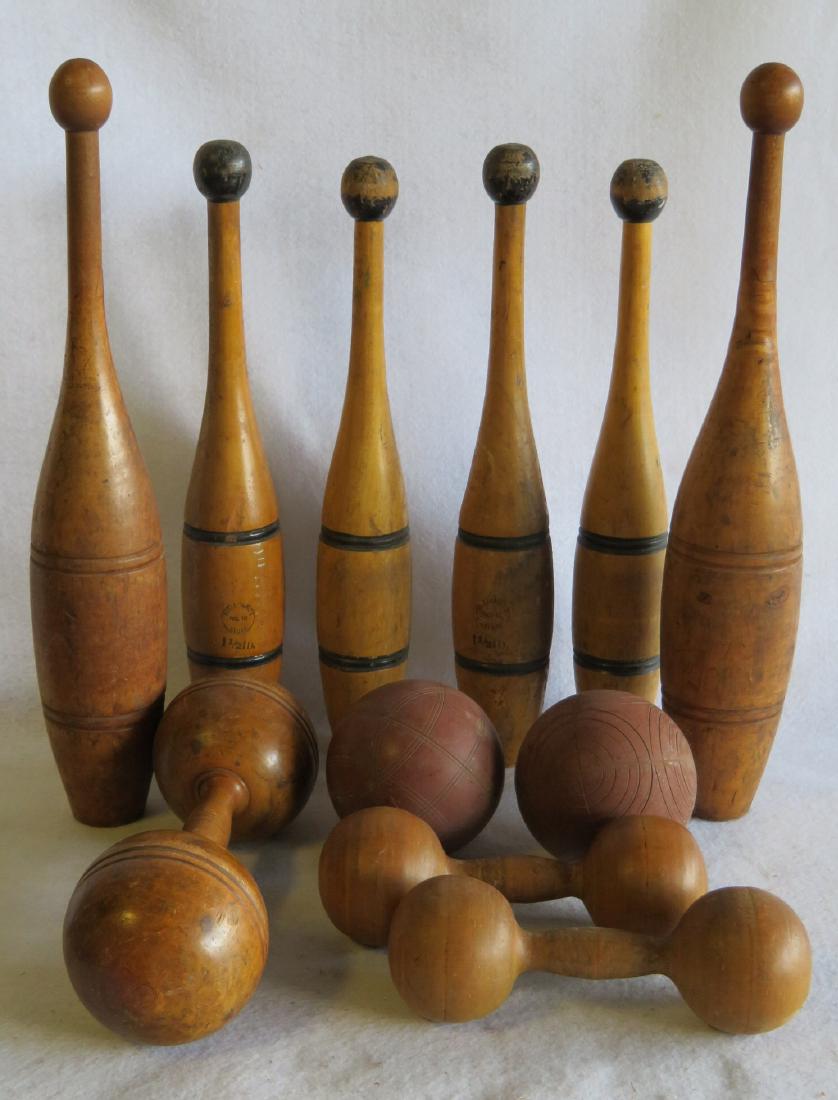 Six wooden juggling pins, 3 dumbbells, and 2 wooden: Six wooden juggling pins, 3 dumbbells, and 2 wooden lawn balls. All late 19th to early 20th century and in used but very good condition. Note 4 matching pins signed Hellenberg's No. 10 Clubs 1 1/2 lb.