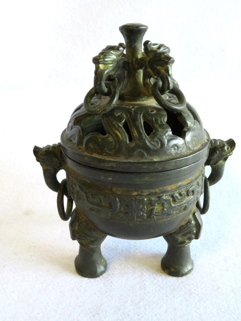 Oriental bronze incense burner with elephant feet,: Oriental bronze incense burner with elephant feet, stylized dolphin head handles, and 4 dragon shaped ornaments attached to finial. 9.5"H x 8"W. Very good condition with patinated green color. Probabl