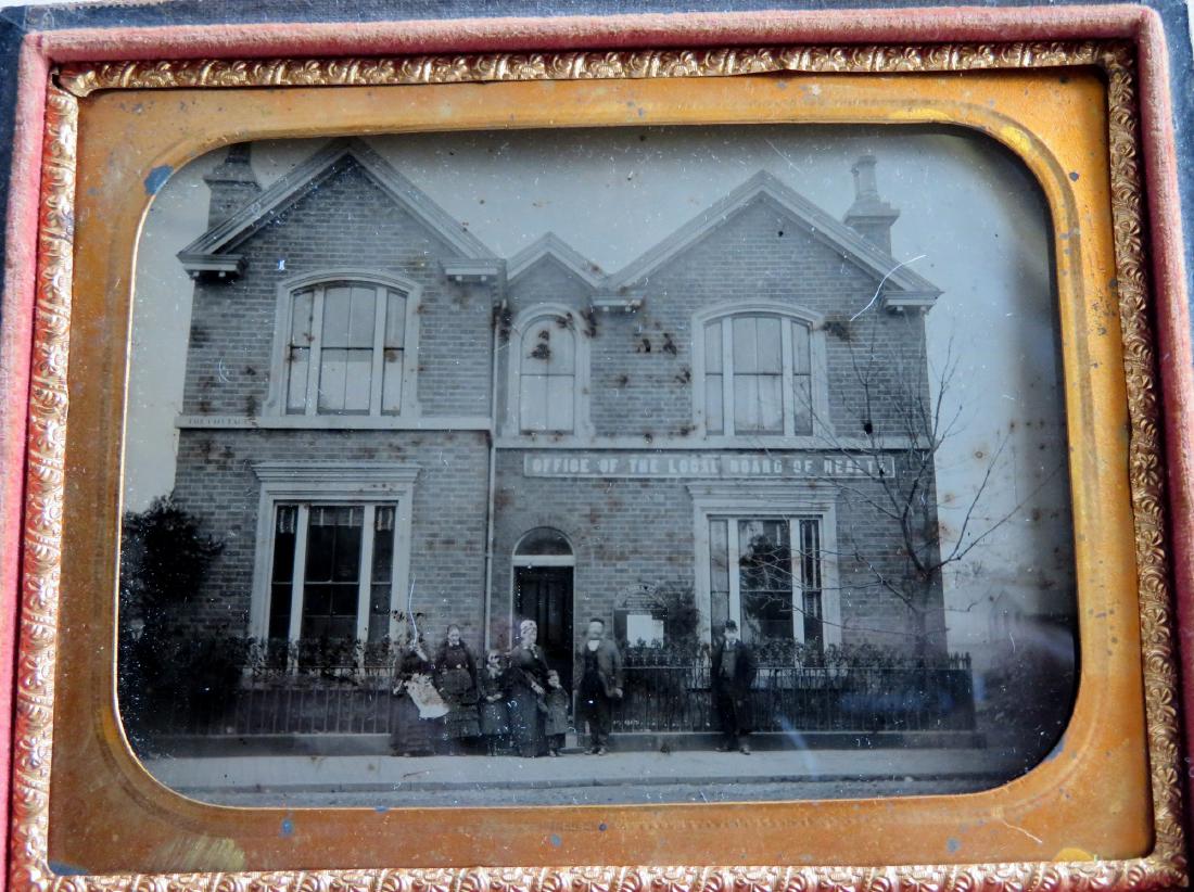 Quarter plate ambrotype of building with sign "Office: Quarter plate ambrotype of building with sign "Office of the Board of Health". The building is also surrounded by an ornate iron fence with people standing in front of it. Slight losses near base of i