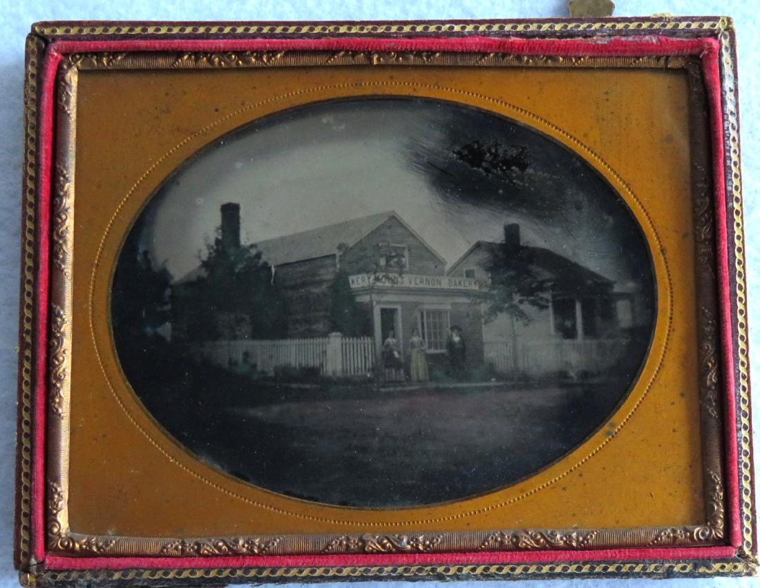 Half plate ambrotype of a building with sign marked: Half plate ambrotype of a building with sign marked "Mount Vernon Bakery" - the building is also surrounded by a white picket fence - 2 women and man standing in front of building - another adjacent b