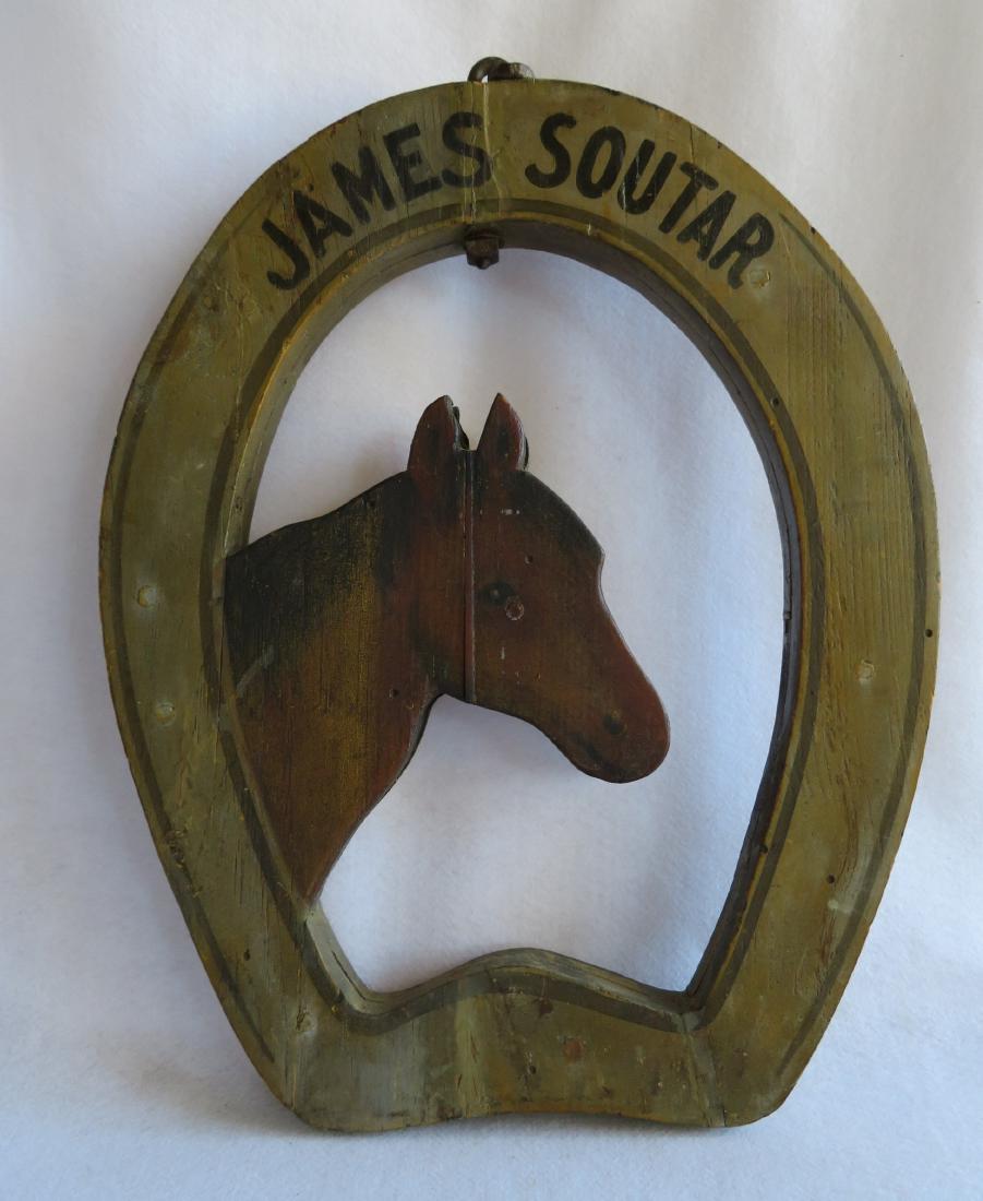 Folk art double sided horse shoe shaped wooden: Folk art double sided horse shoe shaped wooden blacksmith trade sign in original paint, having a carved horse head peering through the "window" of the display - signed "JAMES SOUTAR". The sign has its