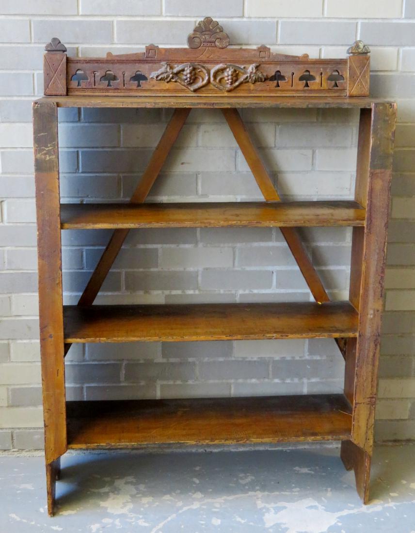 Folk art grain painted floor standing open shelf unit: Folk art grain painted floor standing open shelf unit having a back splash with applied carved grapes and leaves design and boot jack ends. The inside of the case is also in matching grain paint. Late