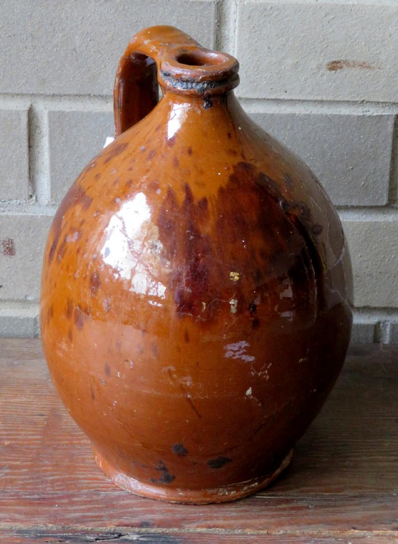 Small redware ovoid jug with manganese decorations.: Small redware ovoid jug with manganese decorations. Several glaze flakes, 2 tight hairlines extending from base of handle, overall good condition. 19th century. 9"H.