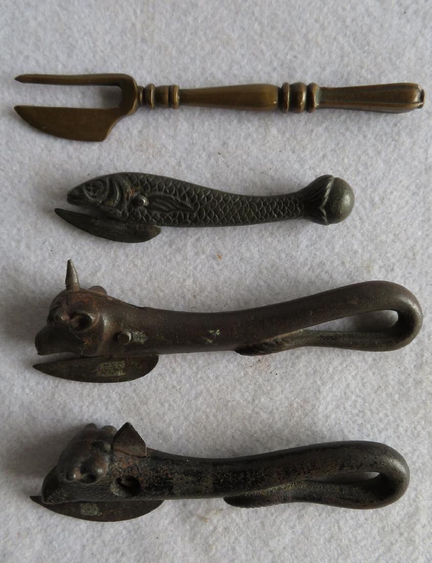 Three figural cast iron can openers, circa 1860-80,: Three figural cast iron can openers, circa 1860-80, including cow's head - 6.75"L, bull's heads - 6.75"L, and 1 in the form of a fish - 5.25"L; together with an 18th century brass cutting tool - 7"L. 