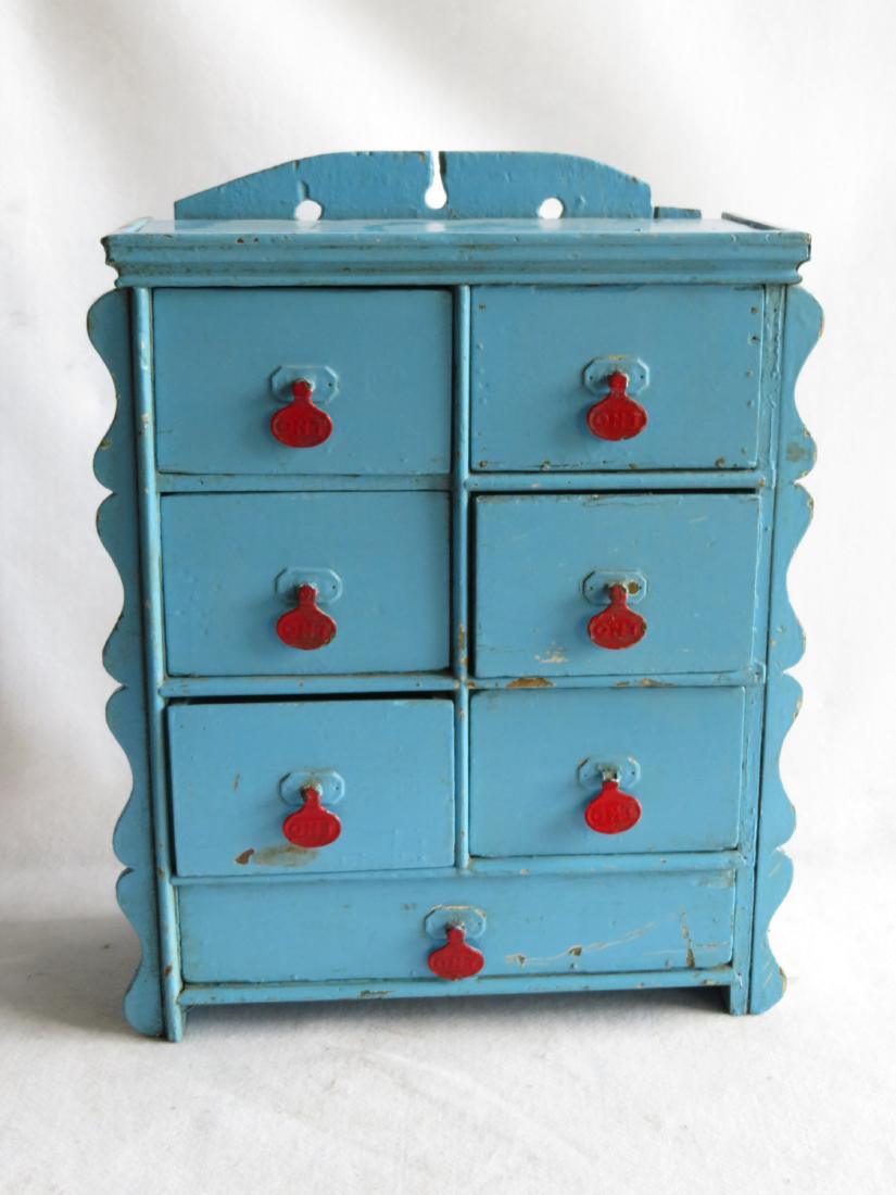 Old wall hanging 7 drawer spice cupboard with many: Old wall hanging 7 drawer spice cupboard with many layers of old paint, the top layer being blue - scalloped sides and spool-cabinet pulls signed O.N.T. Very good condition - 19th century - 15.5"W x 7
