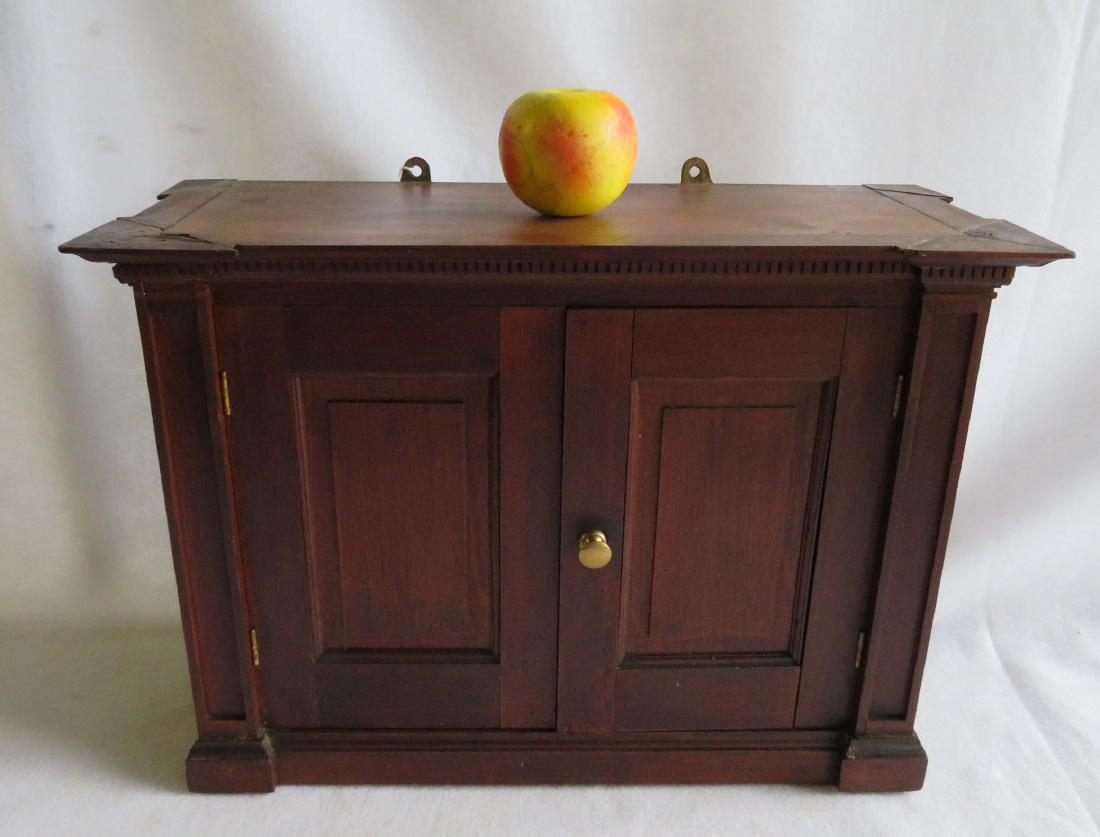 Architectural 2 door cherry wall cupboard in the shape: Architectural 2 door cherry wall cupboard in the shape of a miniature Kas with shaped dental molding across the top, fitted interior, the corners are column shaped, and also has 2 paneled doors. Mid t