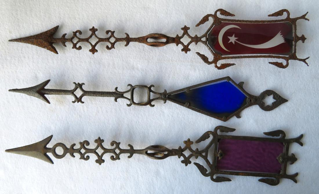 Three lighting rod arrows including: 1) Rippled: Three lighting rod arrows including: 1) Rippled cranberry glass feather- 22.75"L; 2) Cranberry glass feather with cut to clear crescent moon and comet - 23"L; 3) Cobalt blue feather - 21.5"L. Two with