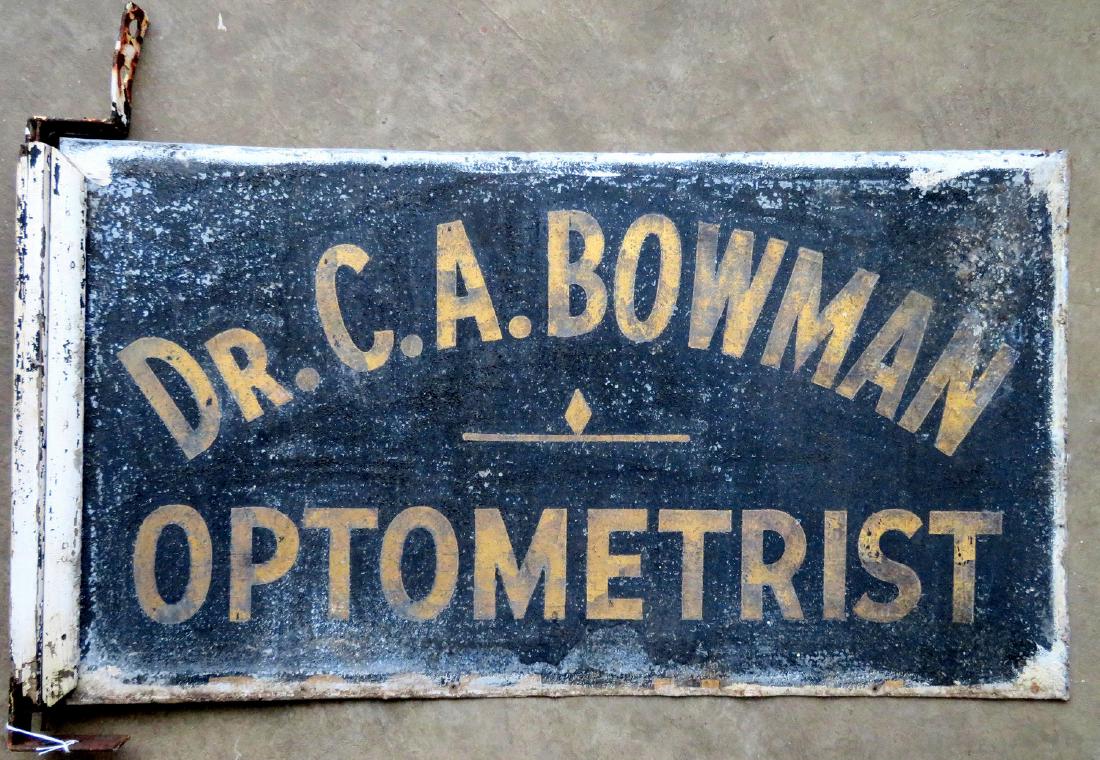 Three signs for "Dr. C.A. Bowman - Optometrist",: Three signs for "Dr. C.A. Bowman - Optometrist", including one in tin with sand paint, double sided with gold lettering on black background - 29" x 16" - partial frame and original mounting bracket - 