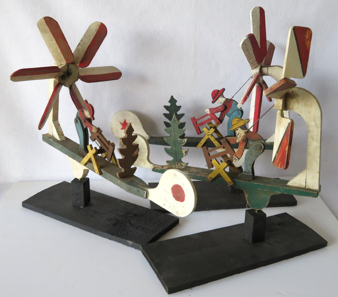Three folk art whirligigs of man sawing log adjacent to: Three folk art whirligigs of man sawing log adjacent to an evergreen tree, all in original colorful paint, early to mid 20th century. All barn found and in original unused condition. The largest 25"L 