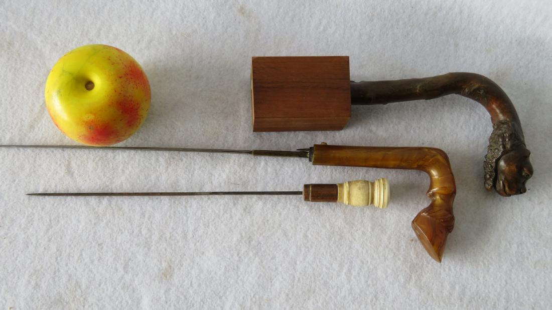 Three carved cane handles: 1) Burl wood with carved dog: Three carved cane handles: 1) Burl wood with carved dog head with glass eyes, mounted on museum wooden stand - 6"H x 4"W; 2) Turned bone handle dagger (missing cane) - 11.75"L; 3) Carved bone handle i