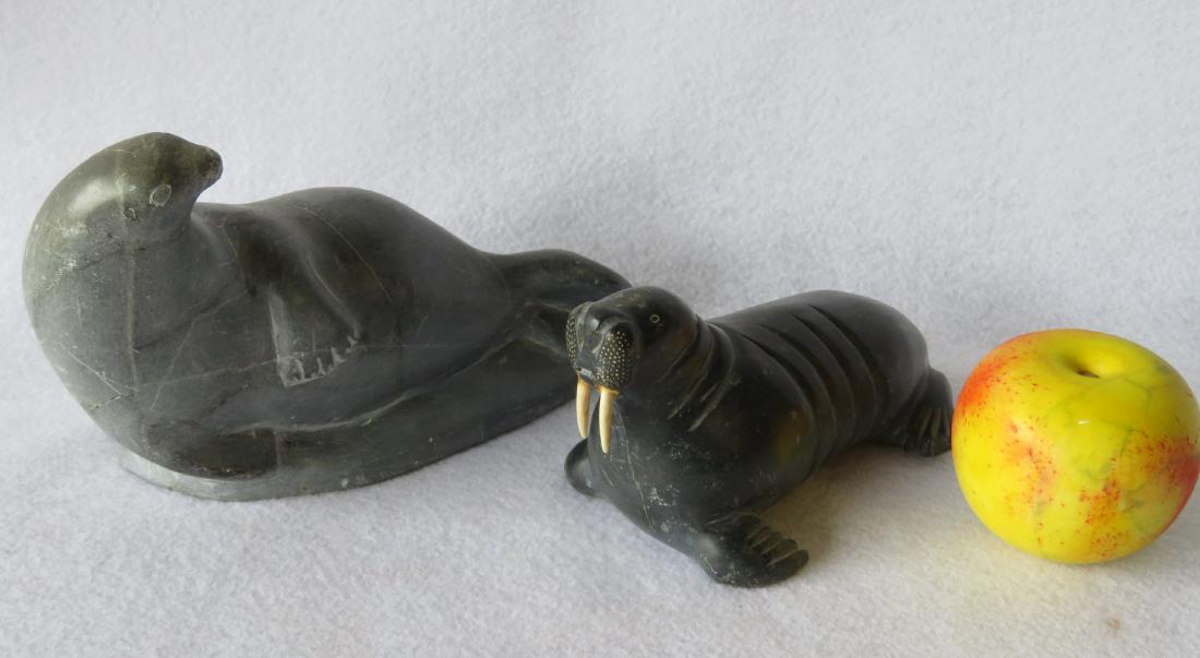 Two Inuit animal sculptures including a large seal 9"L: Two Inuit animal sculptures including a large seal 9"L x 5.5"H - very good condition; and a walrus with bone tusks - marked on base E9864 followed by scratched illegible signature - 7"L x 3.5"H - smal