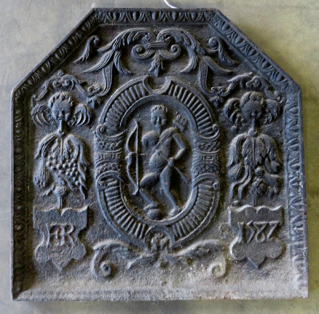 Cast iron 16th century English fireback with shaped: Cast iron 16th century English fireback with shaped top and having a central medallion of Eros, the god of Love, flanked by cherubs, leaves and other ornamentations including lower plaques marked ER o