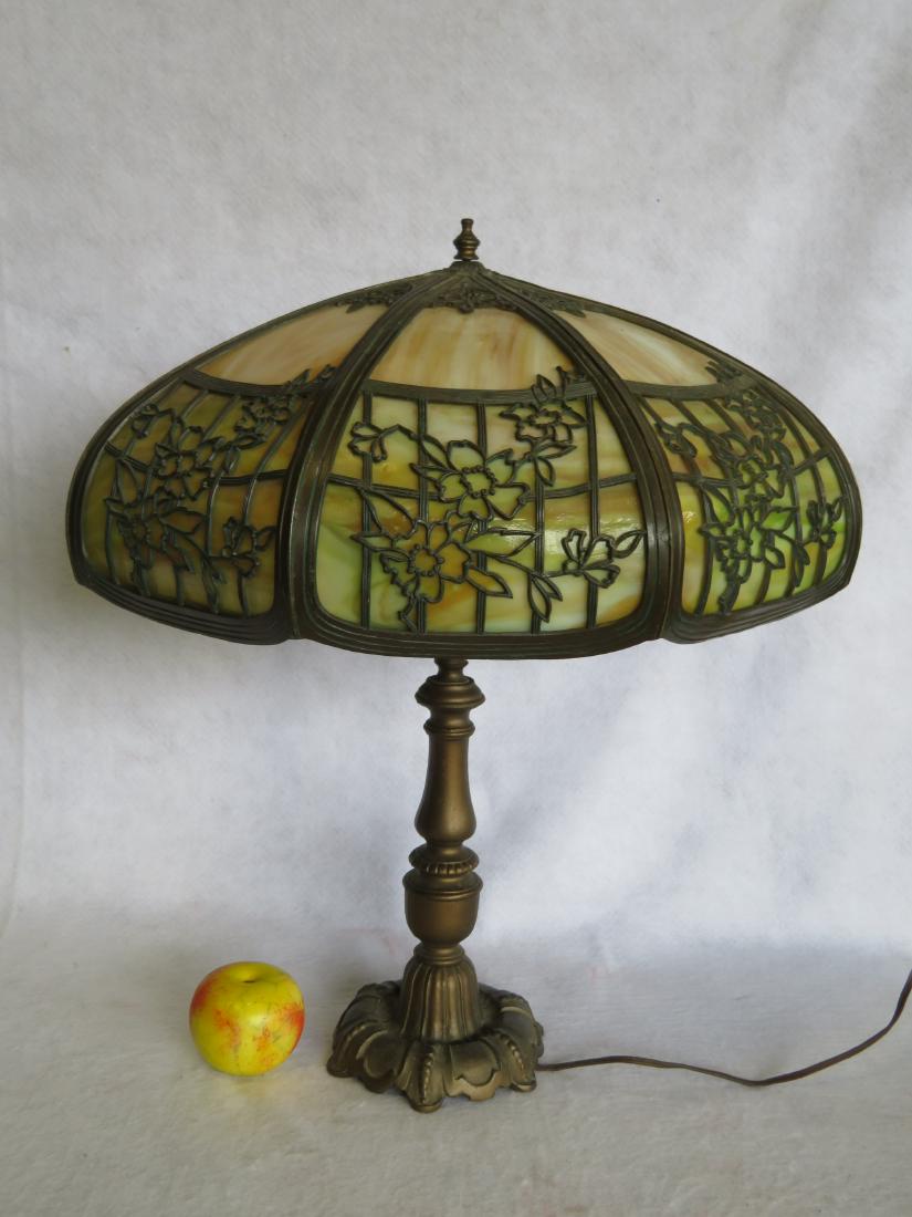 Slag glass table lamp with amber/brown curved glass: Slag glass table lamp with amber/brown curved glass panels under reticulated metal floral decorations on exterior of shade - faux bronze turned post. Very good condition. Shade 19 1/2"D x 23"H. Circa 