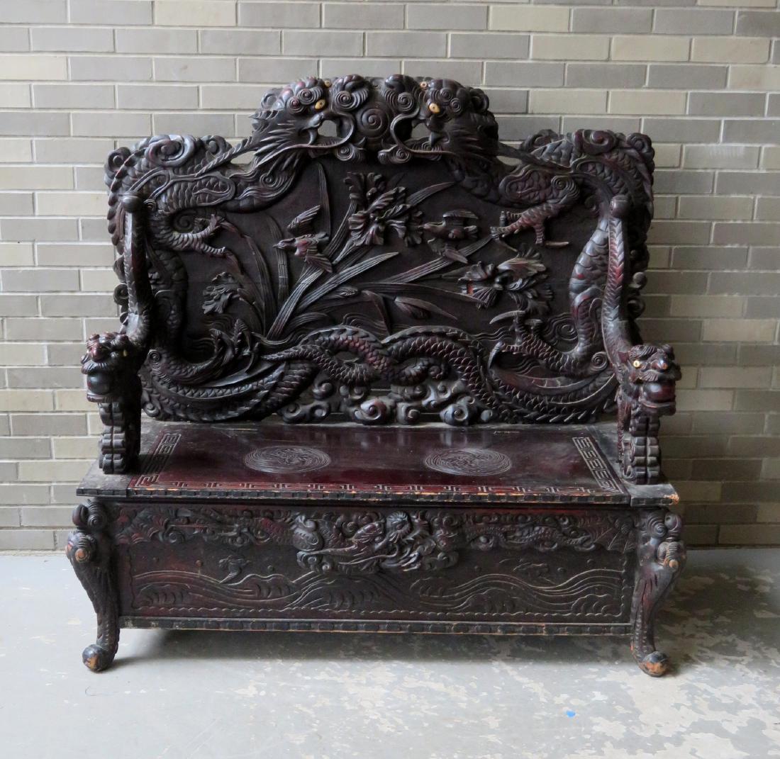 A fine heavily carved oriental dragon hall bench with: A fine heavily carved oriental dragon hall bench with lift top seat, late 19th to early 20th century. The bench decorated with 2 dragons that wrap around the crest and down the sides of the back board