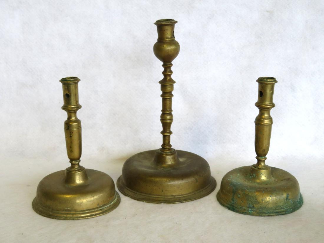 Three 17th century brass candlesticks with dome shaped: Three 17th century brass candlesticks with dome shaped bases, and candle ejector holes, including 2 near matching candlesticks - ranging in size from 7 1/4"H to 10 1/4". Provenance: From a private col