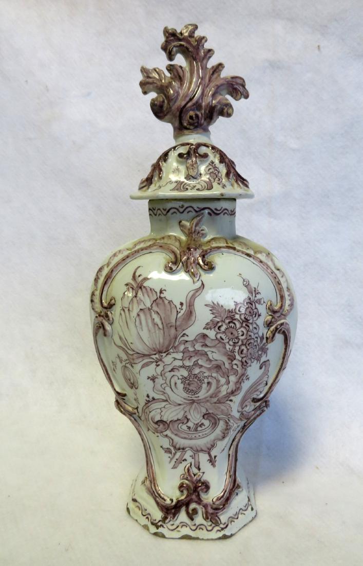 A Dutch delft mulberry color vase with octagonal shaped: A Dutch delft mulberry color vase with octagonal shaped lid that appears to be original. The center medallion of flowers surrounded by a raised scrolled border - the backside decorated with a simple f