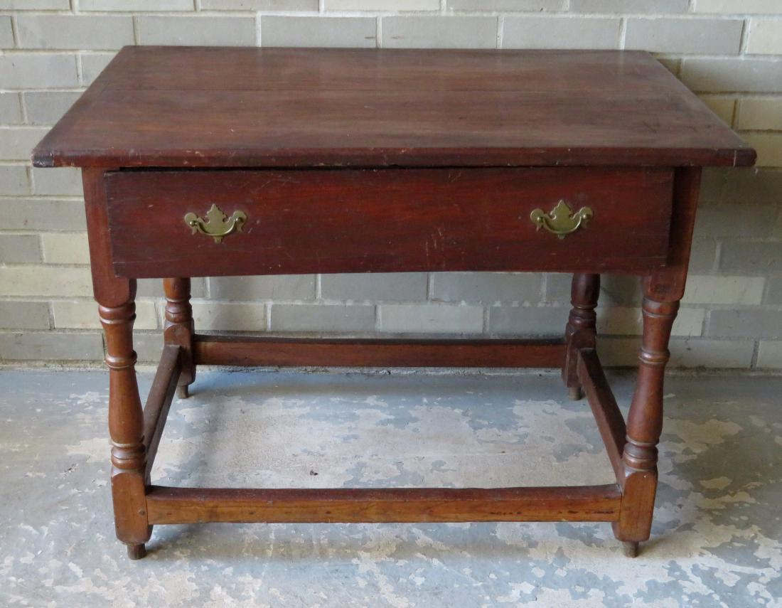 An early tavern table in birch, having a top with: An early tavern table in birch, having a top with breadboard ends over long drawer over turned legs with box stretcher base. The original feet have been replaced with old maple stubs , drawer pull rep