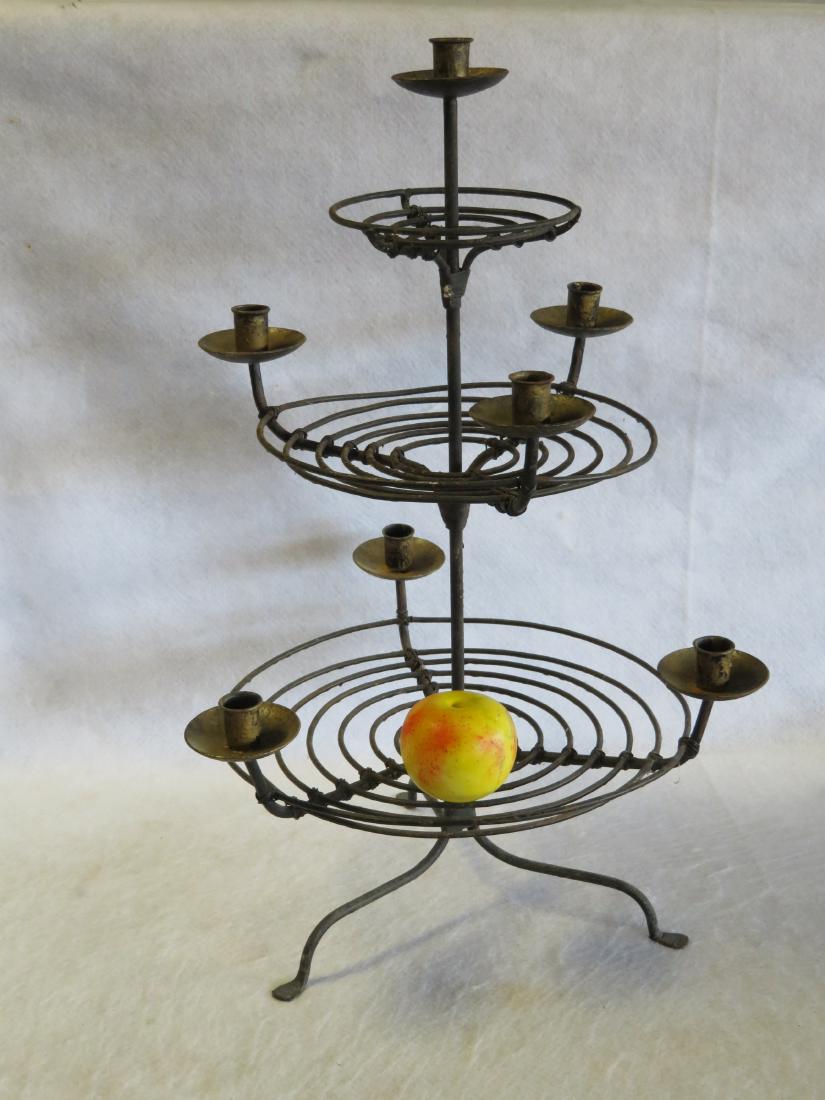 An unusual 3 tier hand made wire table top candle: An unusual 3 tier hand made wire table top candle lighting device having a total of 7 lights, mounted on tripod legs with penny feet. Traces of gold paint on the fonts and overall very good condition.