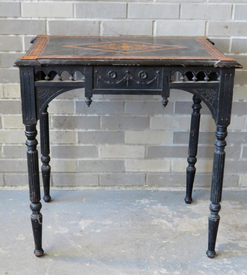 Aesthetic Movement ebonized lamp table with a satinwood: Aesthetic Movement ebonized lamp table with a satinwood inlaid top, carved geometric corners, and an open work carved and spindled apron on all 4 sides, also having reeded and turned legs, late 19th c