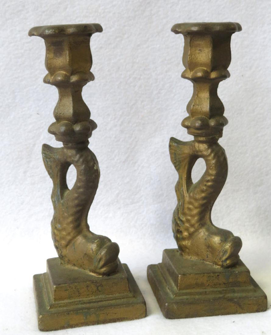 An unusual pair of cast iron dolphin form candlesticks: An unusual pair of cast iron dolphin form candlesticks on a stepped square base, in original gold paint, early to mid 19th century. 9 1/2"H x 5" square at base. Very good condition.