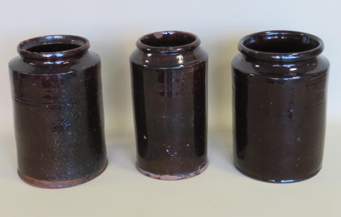 Grouping of 3 redware pantry jars with Albany glaze,: Grouping of 3 redware pantry jars with Albany glaze, 19th century, each approximately 10"H. Two early 19th century and one possibly late 19th to early 20th century. The older with tiny rim chips, else