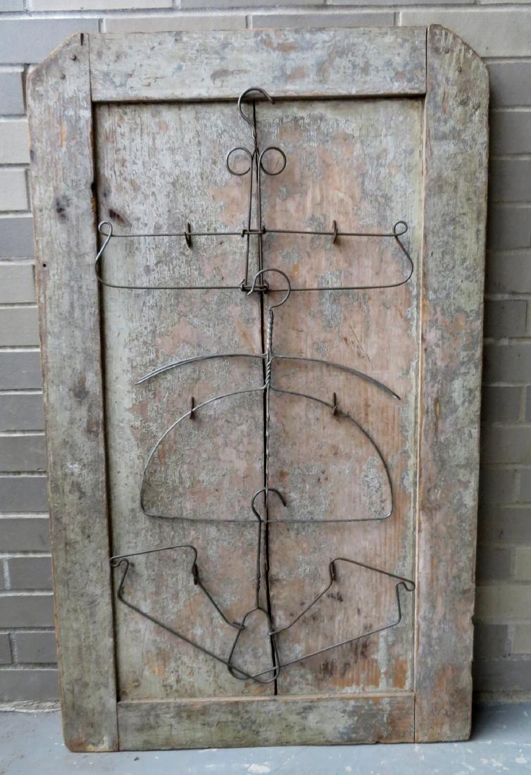 An artistic display of 3 vintage wire coat hangers: An artistic display of 3 vintage wire coat hangers applied to a 19th century door panel scraped down to original green paint - 25 1/2" x 42". Very good condition. Note - All of the artistic displays i