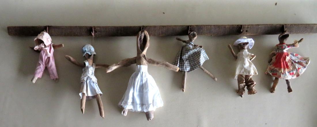 An artistic display of 6 custom made wooden dolls: An artistic display of 6 custom made wooden dolls wearing vintage outfits. The dolls were made from pieces of repurposed drift wood and all creatively mounted on a 19th century tobacco drying rack. Th