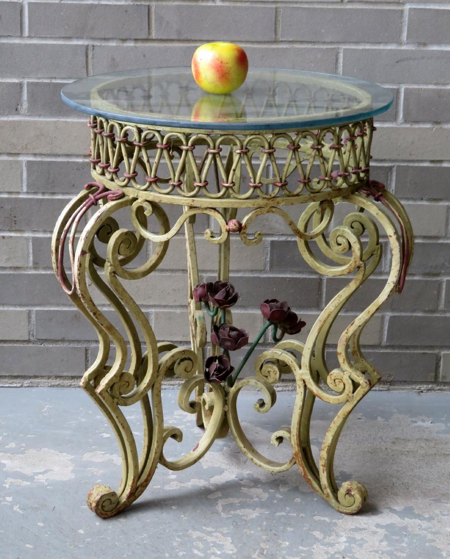 A cast iron patio serving table with round glass top: A cast iron patio serving table with round glass top over 3 elaborate scrolled legs with crimson colored flowers extending from the center of the base - original paint - 18 1/2"D x 24"H. Very good con