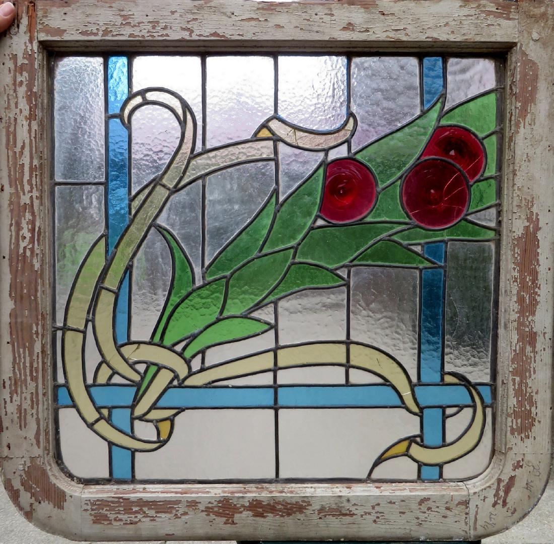 Stained glass window decorated with a stylized flower: Stained glass window decorated with a stylized flower have 3 round red bull's-eye hand blown inserts to represent the flowers - the wooden frame is rounded on one end and squared at the other end. App