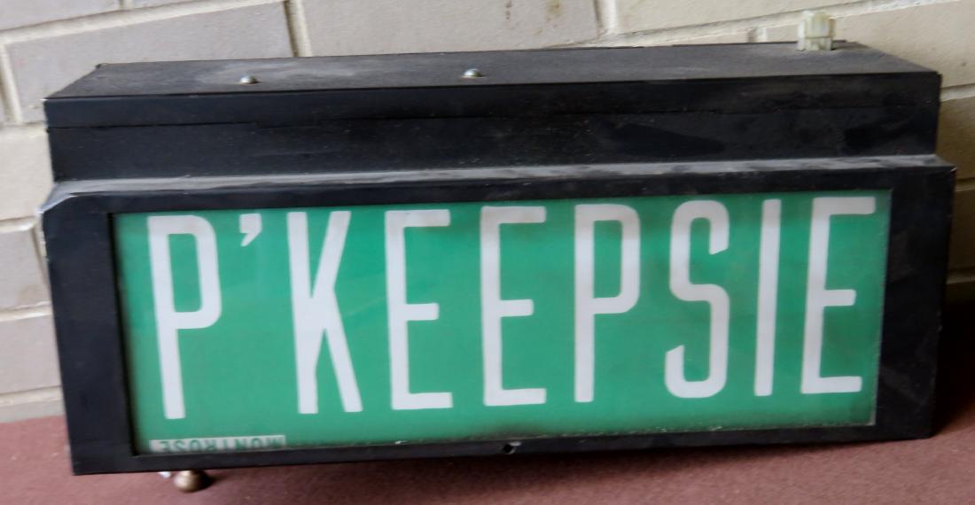 A bus rollup station sign, currently showing: A bus rollup station sign, currently showing "POUGHKEEPSIE" - canvas display in a mechanical metal frame. Note the gear is loose and does not turn to show the stations, otherwise very good condition.