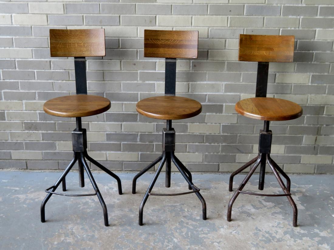 Three custom made industrial oak and iron stools with: Three custom made industrial oak and iron stools with adjustable swivel seats, foot rest and back rest. Late 20th century and all are in very good condition. As shown, approximately 37"H to back of ch