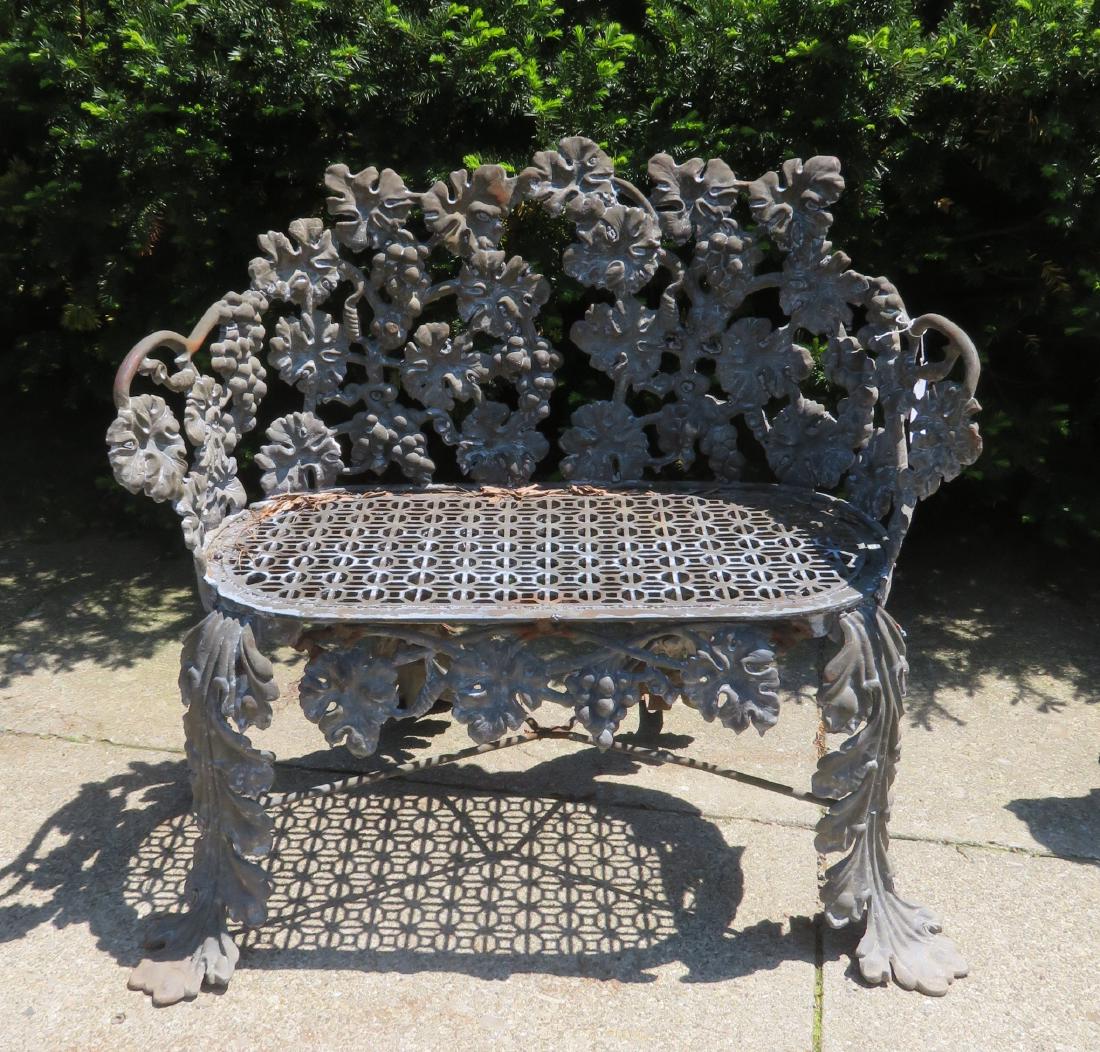 Cast iron garden settee, 19th century.: Cast iron garden settee in grape and leaf pattern with pierced iron seat. This is an original late 19th century version of this popular chair. Note the original iron strap braces to support the legs. 