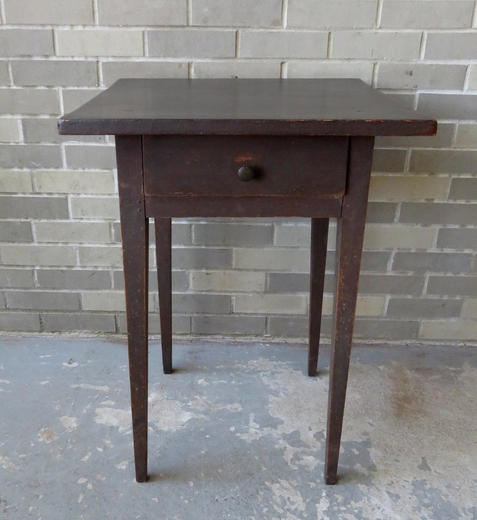 Hepplewhite 1 drawer stand with a darkened red painted: Hepplewhite 1 drawer stand with a darkened red painted surface which appears to be original. The stand also retains its original brass pull, circa 1810. The top 21" square x 29"H. Good condition. Prov
