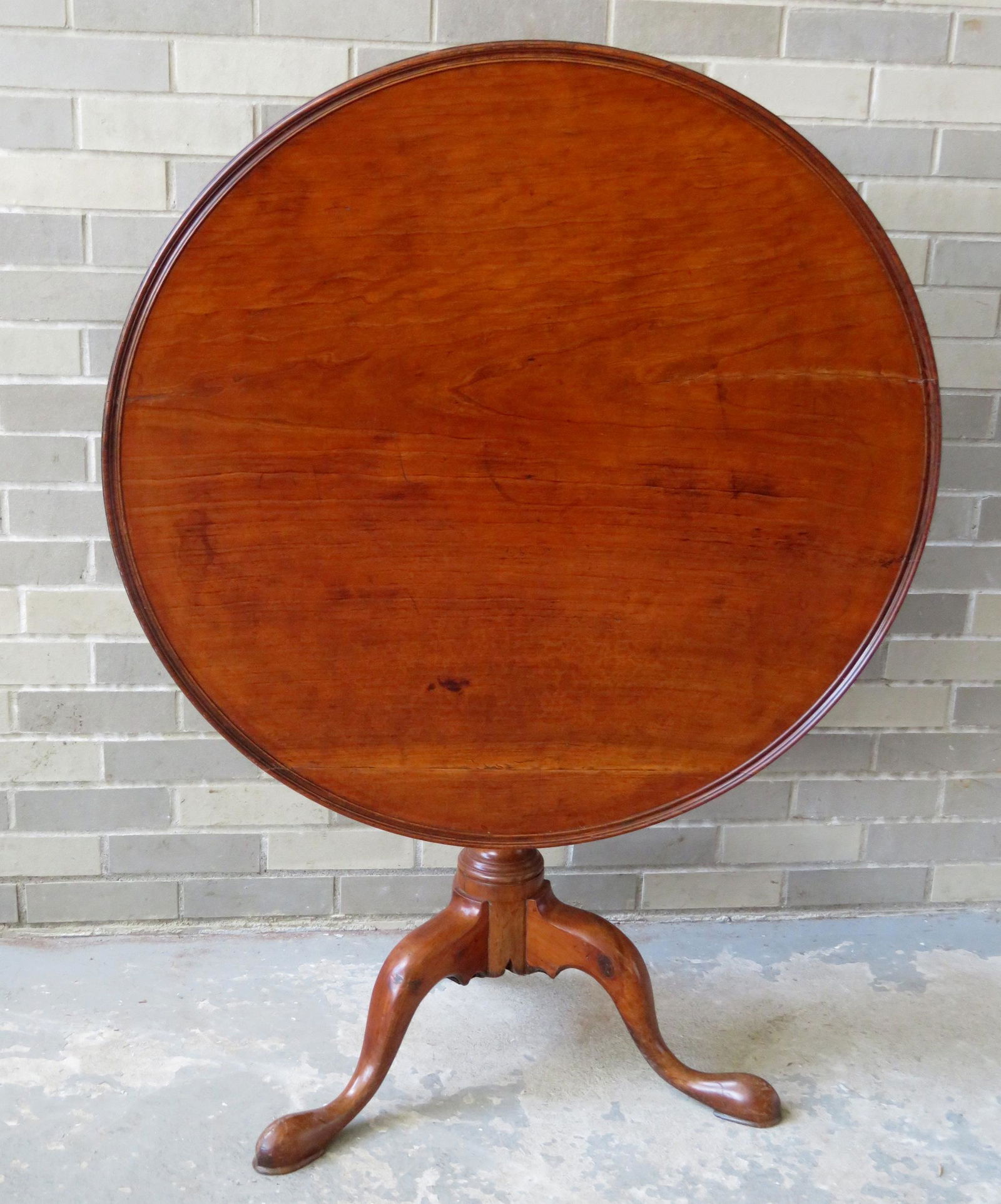Queen Ann cherry tilt-tip tea table with dish top over: Queen Ann cherry tilt-tip tea table with dish top over birdcage over turned column leading to snake feet, 18th century. The top with slight shrinkage hairline, traces of an old black paint, small repa