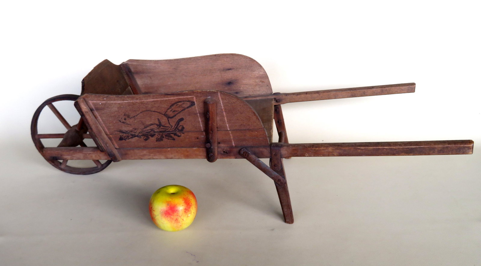 Child's wooden hand made wheelbarrow having stenciled: Child's wooden hand made wheelbarrow having stenciled squirrel on branch applied to sides, late 19th century. Missing small piece of wood from top of backboard, otherwise very good condition. 31"L x 9