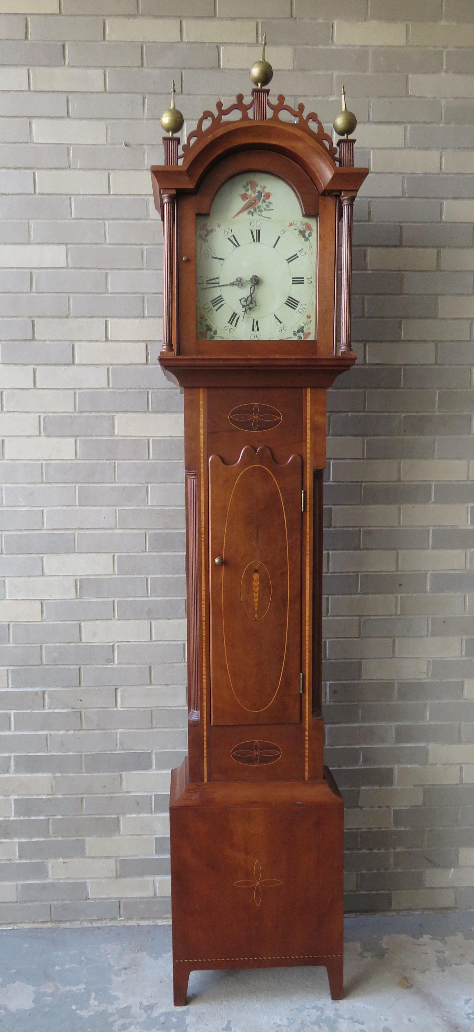 A Hepplewhite cherry tall case clock, circa 1800, with: A Hepplewhite cherry tall case clock, circa 1800, with wooden works and having a hand painted wooden tombstone dial decorated with flowers and a bird on branch with berries, probably Connecticut River