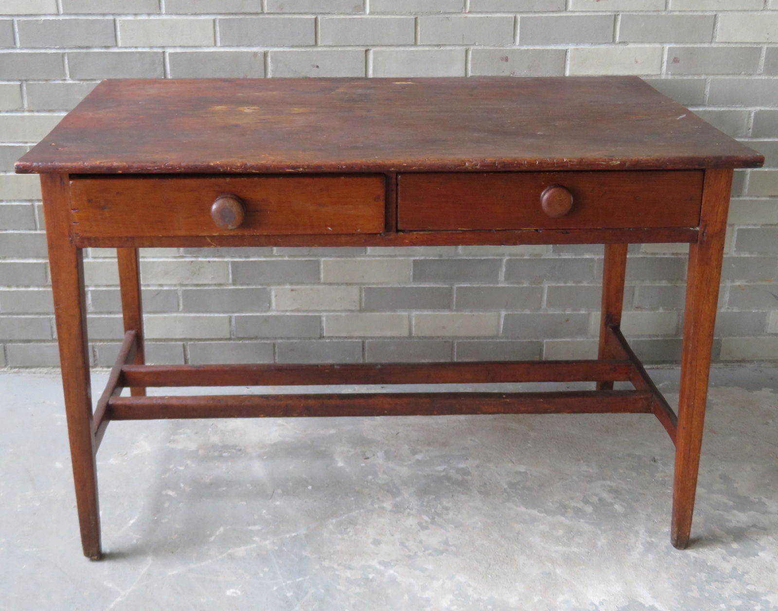 Early pine tavern table having a 1 board top, over 2: Early pine tavern table having a 1 board top, over 2 drawers, tapered legs with double see-through mortised cross stretchers and traces of original red stain. Signs of having a drop leaf on one end. R