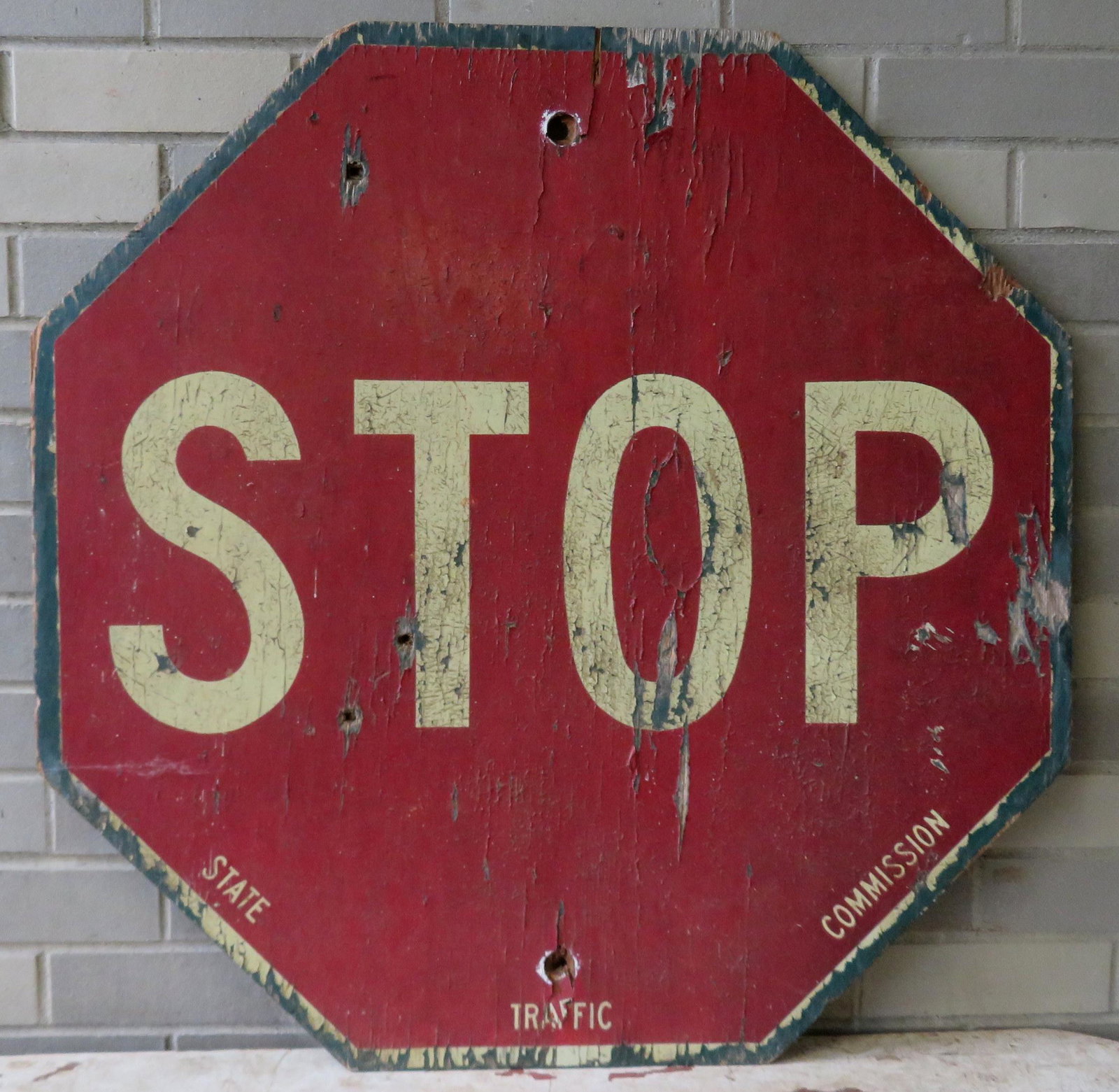 Vintage stop sign in original paint, marked along the: Vintage stop sign in original paint, marked along the base "State / Traffic / Commission". Circa 1930-50. Plywood construction. Paint chips, crazing and mounting bracket holes, all consistent with age