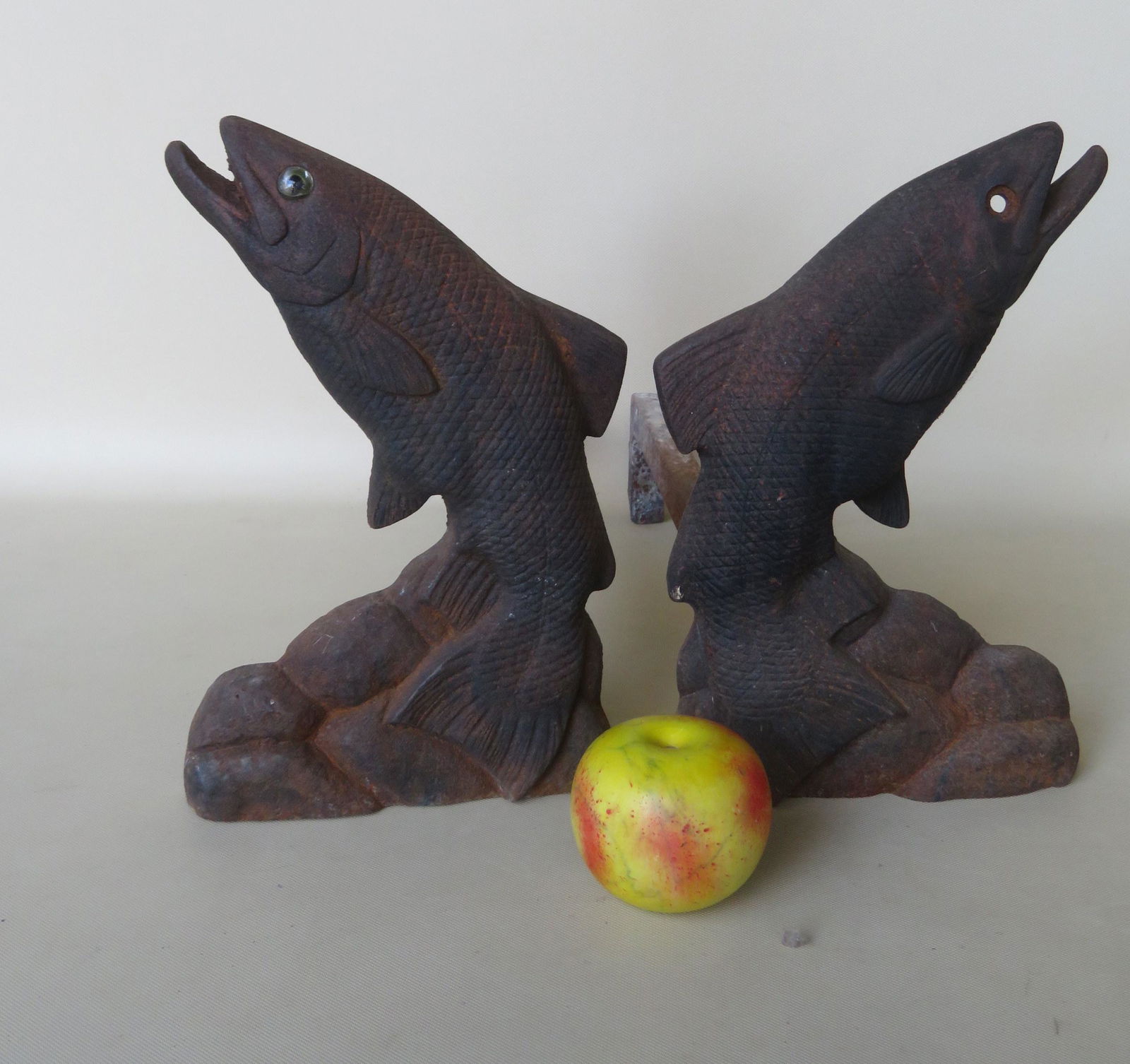 A pair of figural cast iron andirons depicting a: A pair of figural cast iron andirons depicting a leaping trout by stones. Note the excellent details on the body and fins of the fish. One glass eye is missing, replacement bolt on firedogs, otherwise
