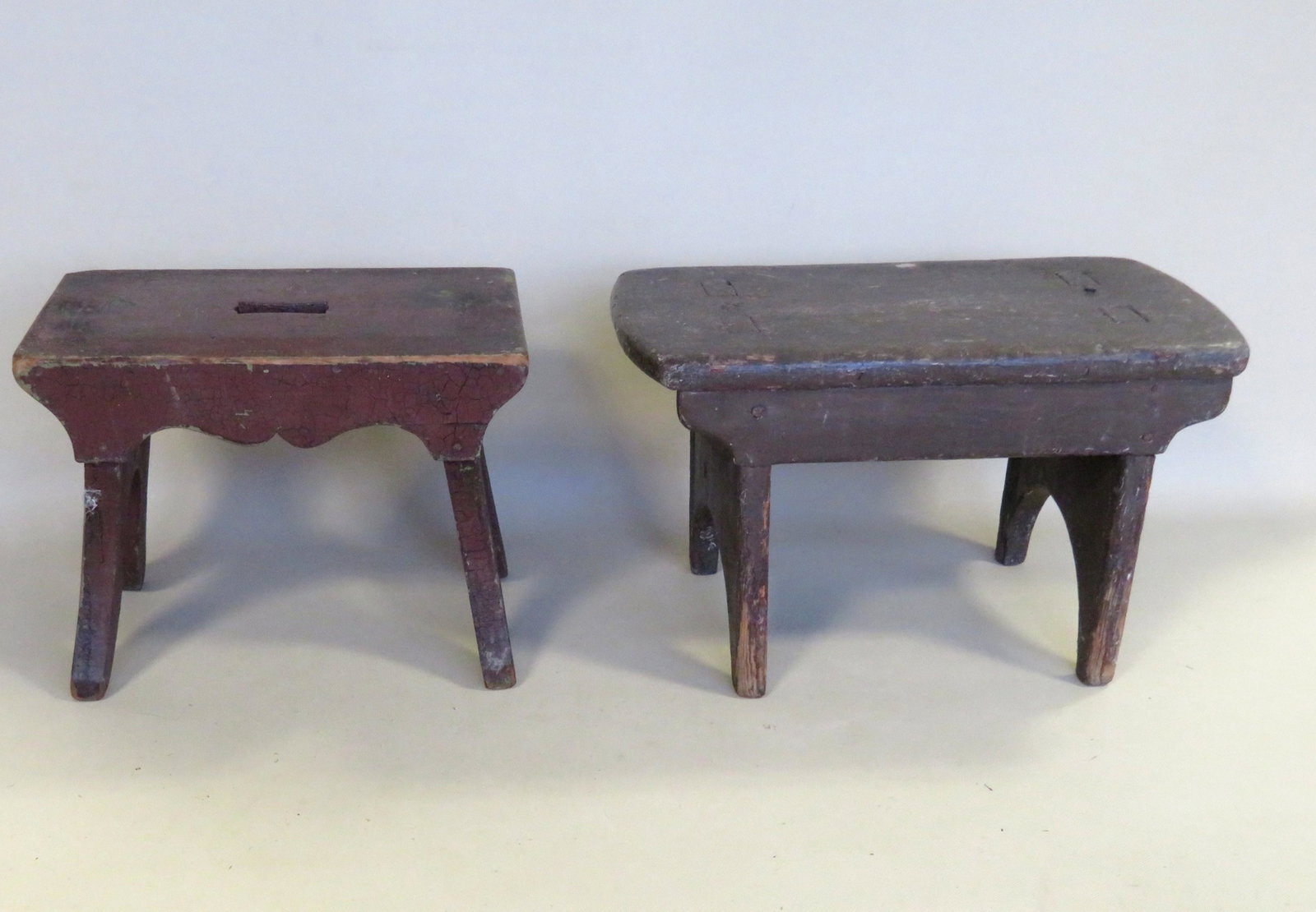 Two primitive cricket stools including: The first with: Two primitive cricket stools including: The first with see through mortise construction, half moon cutouts on sides, and old brown over original blue/green paint - 16"W x 9"D x 9 1/2"H; the second wit