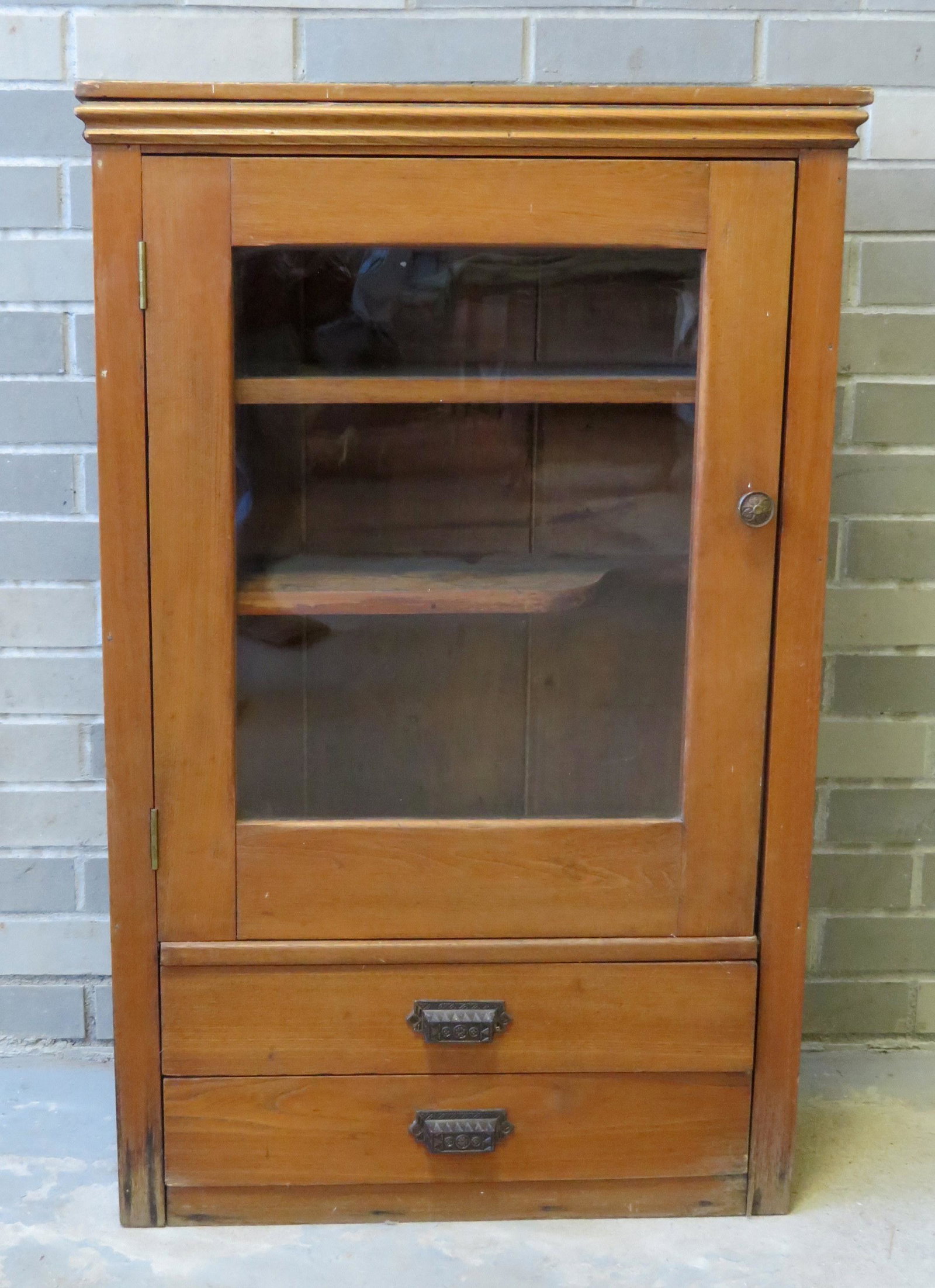 A Victorian chestnut wall cabinet, probably medical in: A Victorian chestnut wall cabinet, probably medical in nature, having a single door over 2 drawers with cast iron pulls. The cabinet with 2 interior shelves, with one shaped to allow for a larger item