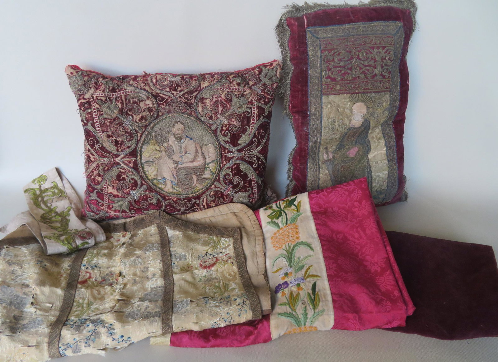 Grouping of 6 early textiles including: Pillow with: Grouping of 6 early textiles including: Pillow with mostly embroidered gold thread and having a circular central image of a seated saint in front of resting cow - the saint's face is hand painted - 19