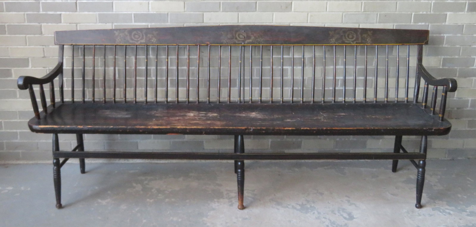 A good Sheraton spindle-back meeting house bench in: A good Sheraton spindle-back meeting house bench in original paint and stenciling, circa 1820. The bench with scrolled arms, saddle seat, and hand forged iron central brace that secures back to seat. 