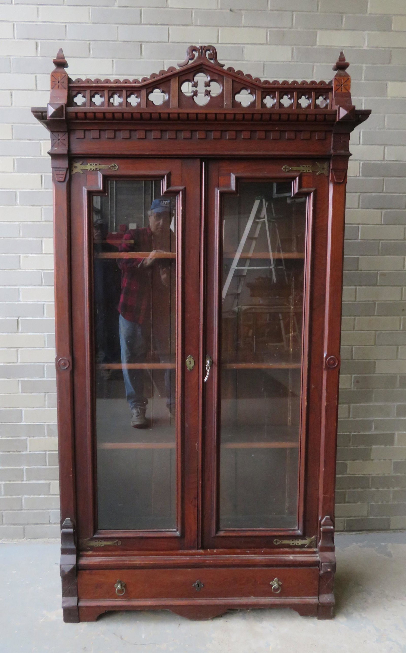 A gothic style Victorian black walnut bookcase, having: A gothic style Victorian black walnut bookcase, having 2 glass doors, over 1 long drawer at base and having adjustable wooden shelves, circa 1870-80. Note the very fine exposed brass strap hinges whic