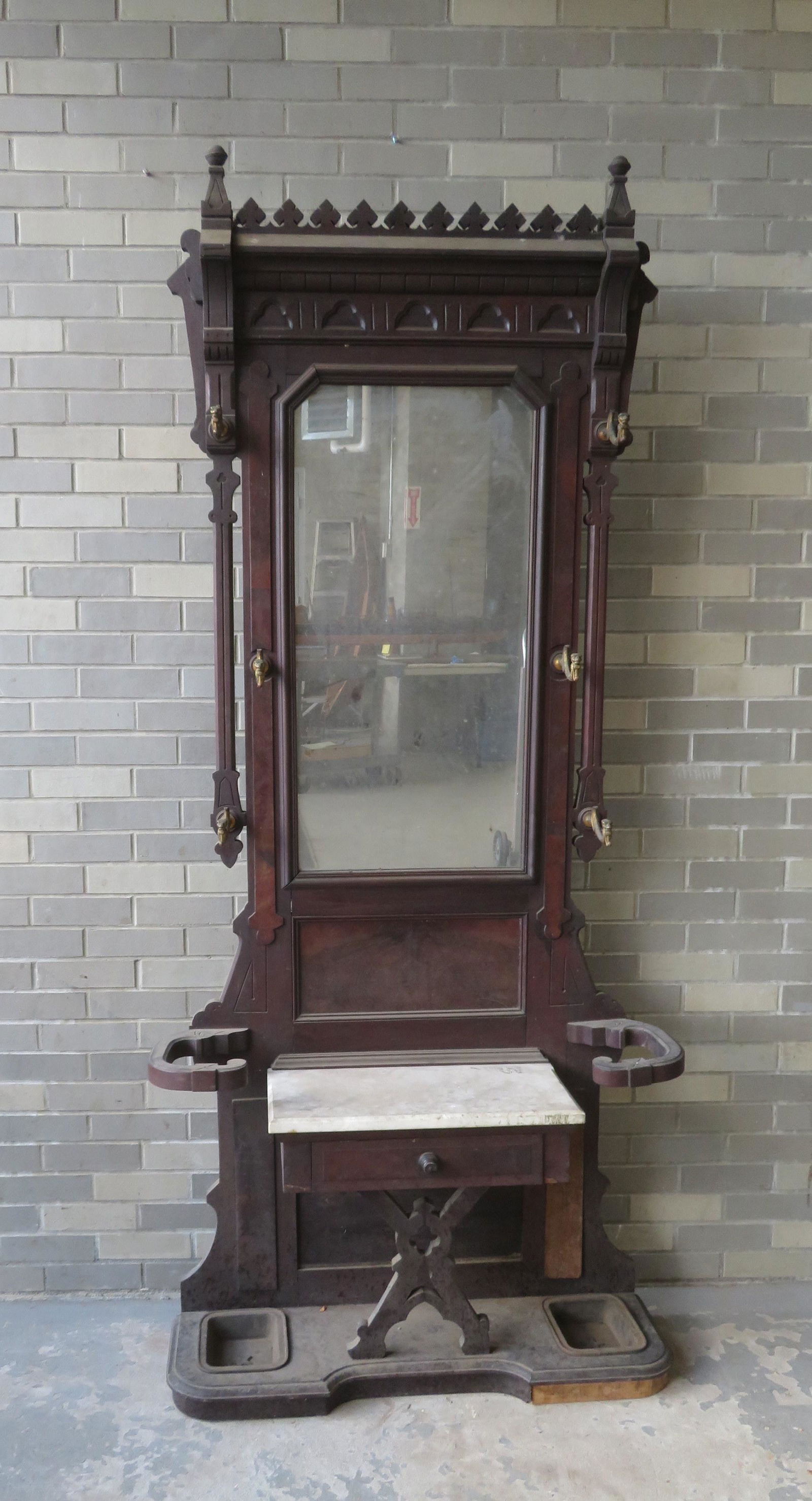 Victorian black walnut hall tree having a large central: Victorian black walnut hall tree having a large central mirror over a marble top with lower drawer, umbrella holders on each side of stand with cast iron inserts at base having embossed stars. The sta