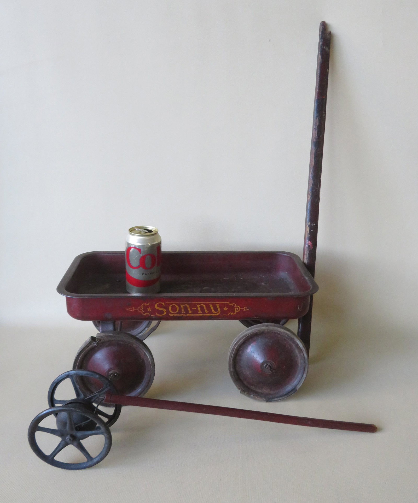 Two child's pull toys including a red sheet metal wagon: Two child's pull toys including a red sheet metal wagon stenciled "Son-ny" in yellow paint and with a wooden handle (loss to end of handle, the rubber on 3 wheels has been replaced, some use wear, ori