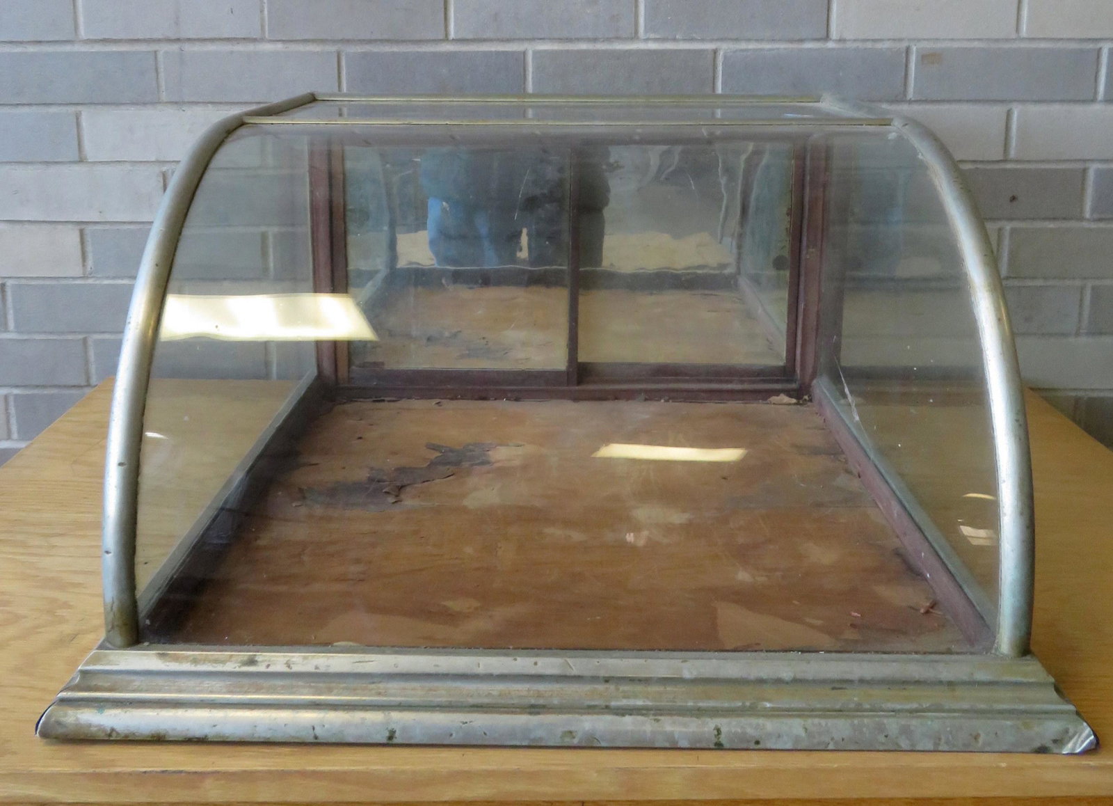 Small table top candy or cigar showcase with curved: Small table top candy or cigar showcase with curved glass front, nickel plated frame, and 2 mirror-back sliding doors. 23"W x 24"D x 13"H. Condition: Hairline crack in top section of glass, some scrat